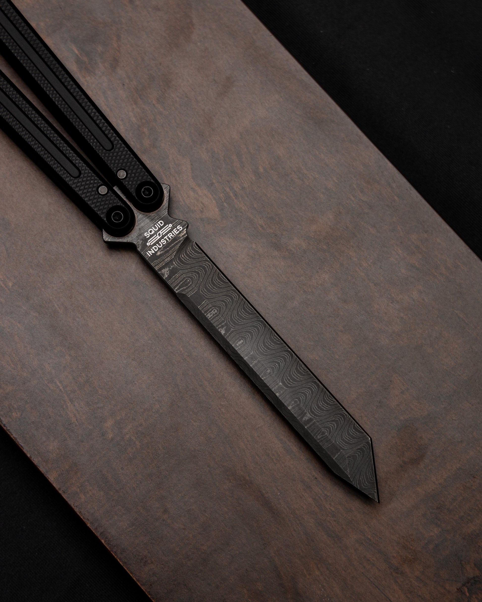 Matte black Damascus open position on wooden table. 