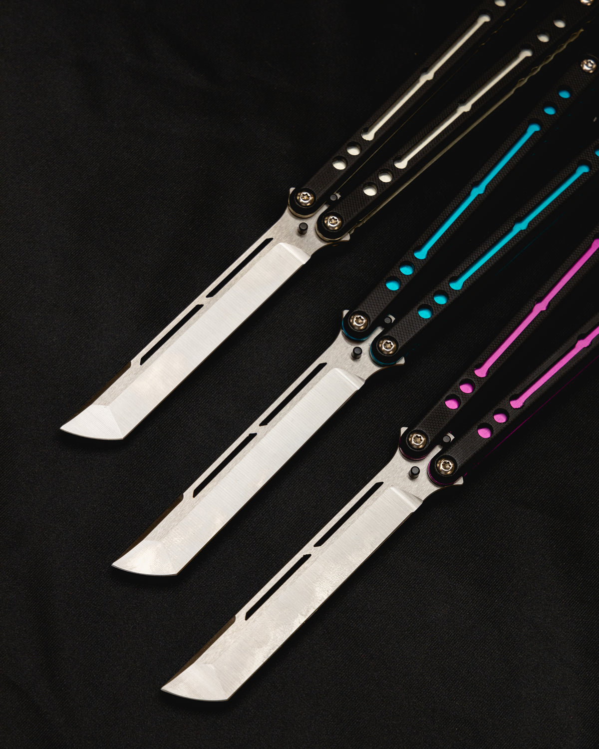 Tanto Nautilus Teal, Magenra and Silver open position side by side on black cloth. 